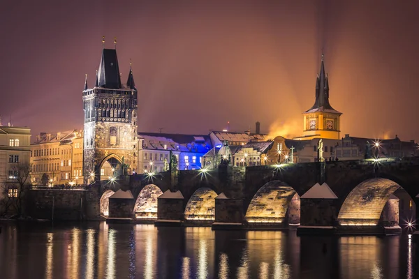 Praga por la noche, Puente de Carlos y su torre desde el otro lado del río . — Foto de Stock