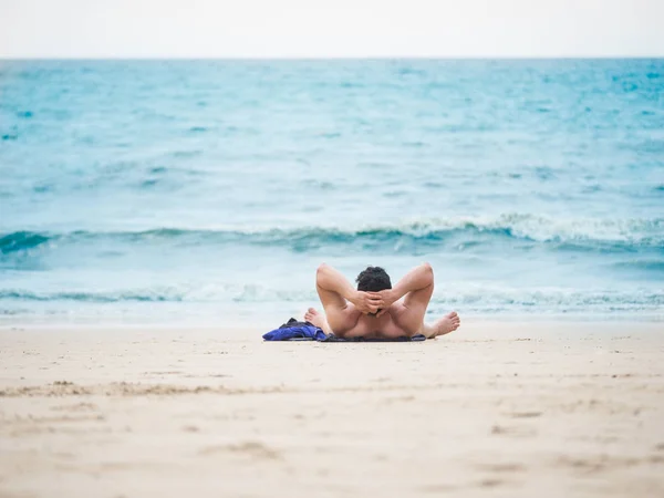 Homme allongé sur la plage profitant de vacances d'été en regardant la Images De Stock Libres De Droits