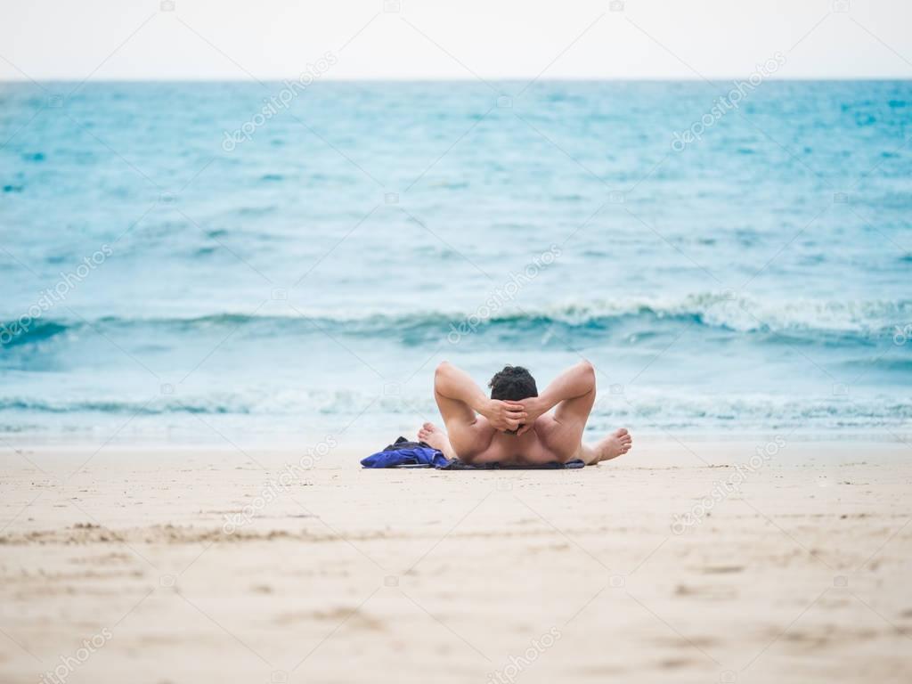 Man laying on the beach enjoying summer holidays looking at the 