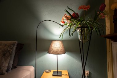 Yatak odasının içinde saat saksısı ve ahşap masa var.