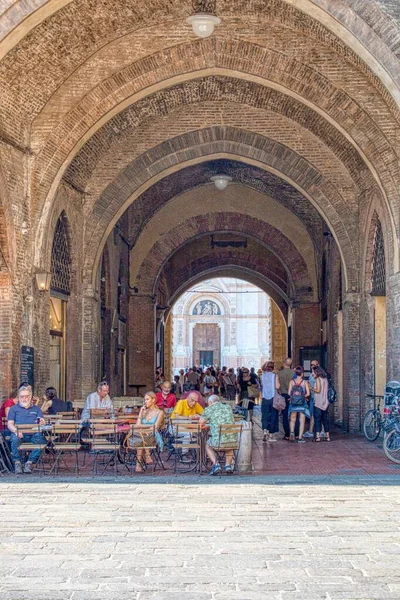 Turistas bajo el pórtico de Piazza Maggiore en Bolonia, Italia — Foto de Stock