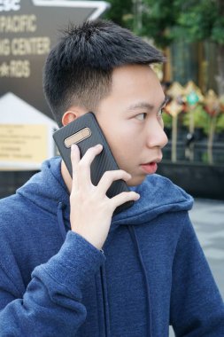 Yaklaş yakışıklı adam. Doğa bahçesindeki telefonu ara.