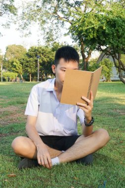 Taylandlı çocuğu kapatın ve doğa bahçesinde kitap okuyun.