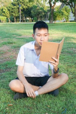 Taylandlı çocuğu kapatın ve doğa bahçesinde kitap okuyun.