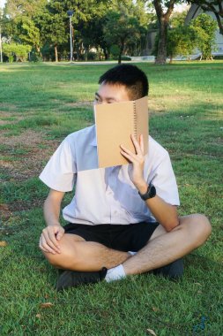 Taylandlı çocuğu kapatın ve doğa bahçesinde kitap okuyun.