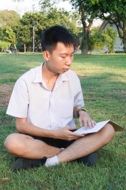 Taylandlı çocuğu kapatın ve doğa bahçesinde kitap okuyun.