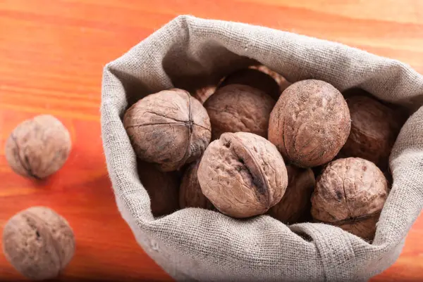 Sáček s ořechy na dřevěné pozadí — Stock fotografie