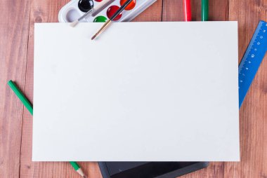 Tablet, boyalar, kalemler ve kopya alanı ile beyaz kağıdın altında işaretleri