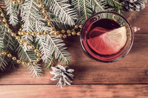 Mug with mulled wine, fir branches on wooden background. Vintage style