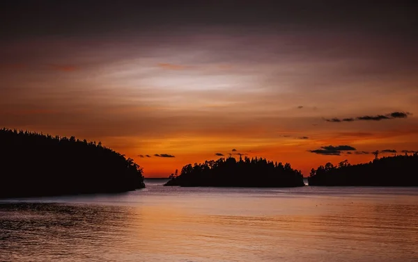 Pôr do sol no mar. Céu vermelho escuro e ver os contornos das ilhas no mar — Fotografia de Stock
