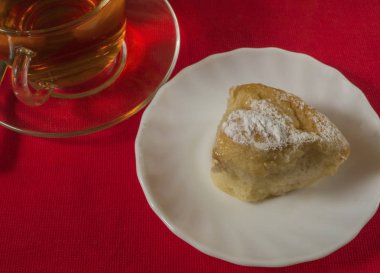 Bir kek ve bir bardak çay kırmızı plaka üzerinde. Yakın çekim.