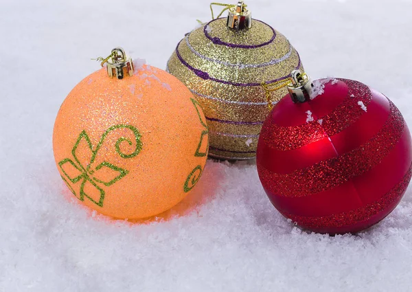 Bakgrund av tre julgranskulor på snö. — Stockfoto