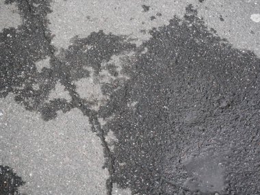 Siyah asfalt su birikintisi ile yağmur sonrası kırık. 