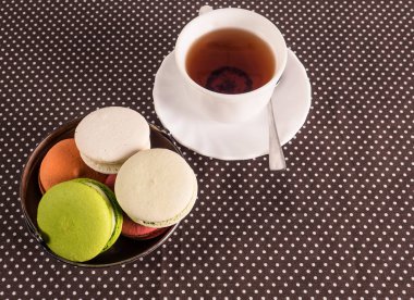 fincan çay ve bir sepet macarons masada.