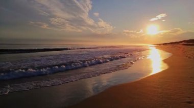 Altında belgili tanımlık deniz dalgaları ile parlak günbatımı sıçramalarına