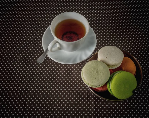 Tasse Tee und ein Korb Macarons auf dem Tisch. — Stockfoto