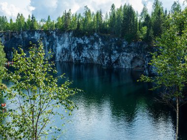 Karelia 'daki Mermer kireç taşı kanyonunda güneşli bir gün. Su basmış taş ocağının turkuaz suyla manzarası