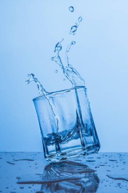 Bir bardak su mavi bir arka plan üzerinde sıçrama