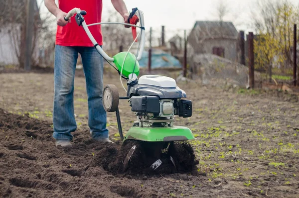 Hombre trabajando en el jardín de primavera con la máquina de timón — Foto de Stock