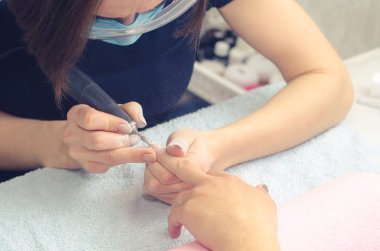 Asıl manikür için makinasıyla manikür çivi hazırlar