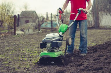 Bahar bahçede tiller makine ile çalışan adam