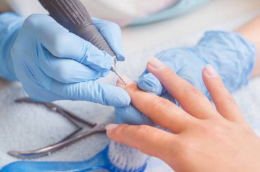 Lastik eldiven manikür ustası bir manikür, tırnak cilası makine yardımıyla bir kadın üzerinde çivi yapar.