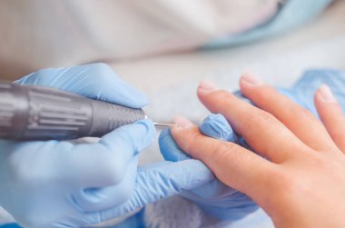 Lastik eldiven manikür ustası bir manikür, tırnak cilası makine yardımıyla bir kadın üzerinde çivi yapar.