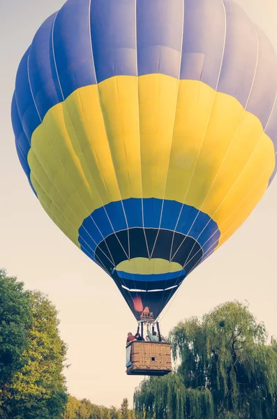 Kolorowe z gorącym powietrzem balon zdejmuje nad drzew — Zdjęcie stockowe