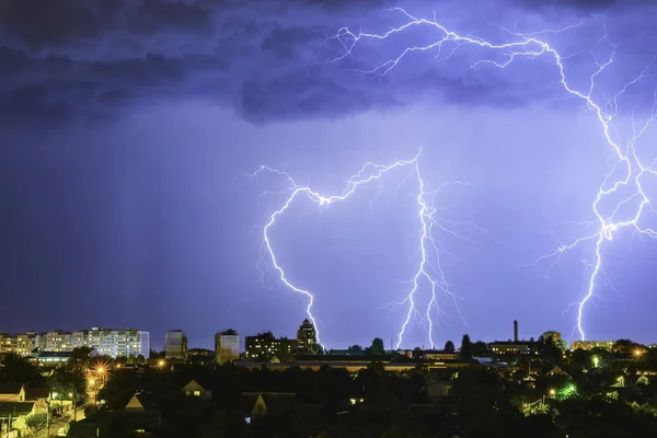 Lightning over the city in the night sky strikes the roof of the house — Stock Photo, Image