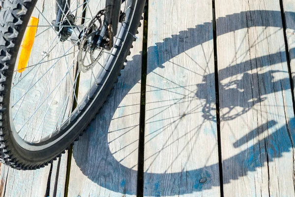 Schatten von einem Fahrradrad auf einem hölzernen Hintergrund — Stockfoto
