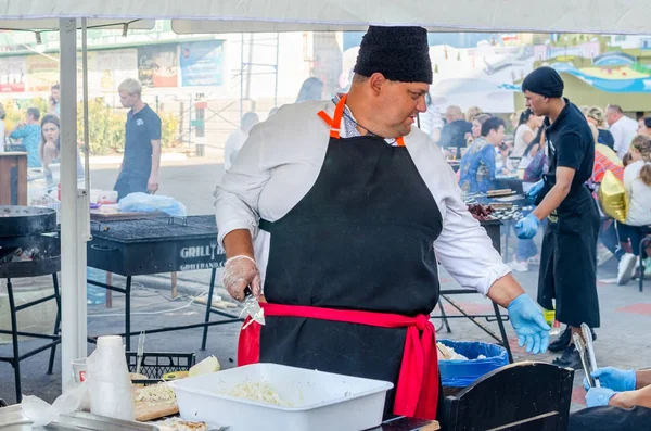 16 settembre 2017 Ucraina, Chiesa Bianca. Un uomo grasso cuoco in un grembiule nero prepara il cibo per strada — Foto Stock