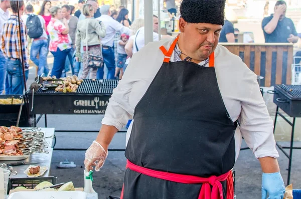 16 settembre 2017 Ucraina, Chiesa Bianca. Un uomo grasso cuoco in un grembiule nero prepara il cibo per strada — Foto Stock