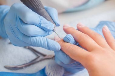 Lastik eldiven manikür ustası bir manikür, tırnak cilası makine yardımıyla bir kadın üzerinde çivi yapar.