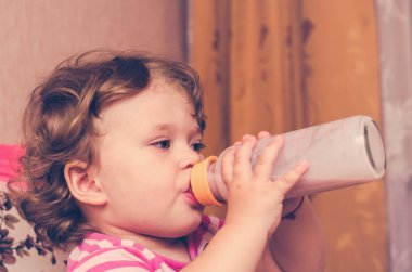 Küçük kız bir şişe süt içiyor