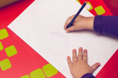 Kırmızı tablo, çocuk el ile renkli kalemler ve boş bir sayfa