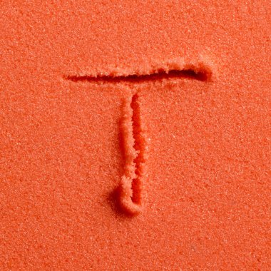 Turuncu kum üzerinde Yazılı T harfi