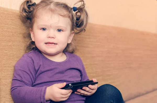 Menina jogando smartphone sentado no sofá — Fotografia de Stock