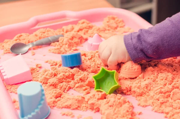 Kinetik kumla oynayan bir çocuğun elleri.