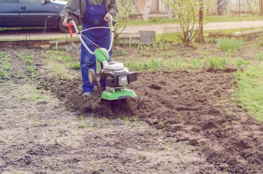 Bahar bahçede tiller makine ile çalışan adam