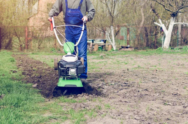 Uomo che lavora nel giardino primaverile con macchina fresatrice — Foto Stock