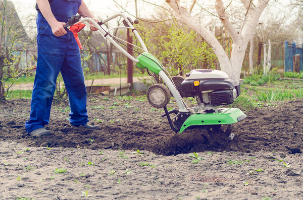 Man working in the spring garden with tiller machine