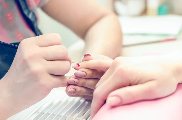 Manicurist paints nails with red lacquer in the salon — Stock Photo, Image