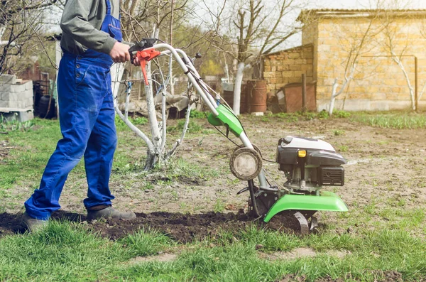 Homem trabalhando no jardim da primavera com máquina de leme — Fotografia de Stock