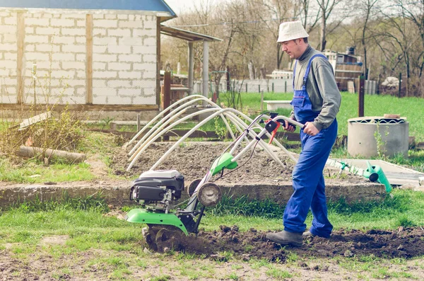 Uomo che lavora nel giardino primaverile con macchina fresatrice — Foto Stock