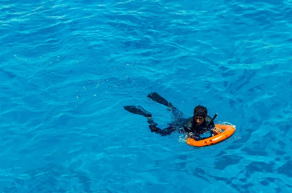 Sharm El Sheikh, Egipto, 8 de mayo de 2019: un joven con boya salvavidas nada en agua azul marino — Foto de Stock