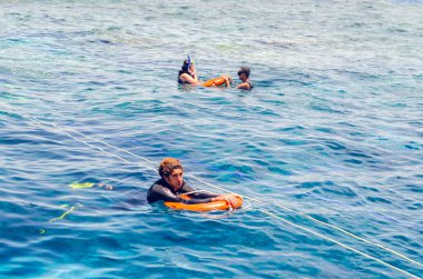 Sharm El Sheikh, Mısır, 8 Mayıs 2019: can simidi olan genç adam mavi denizde yüzüyor