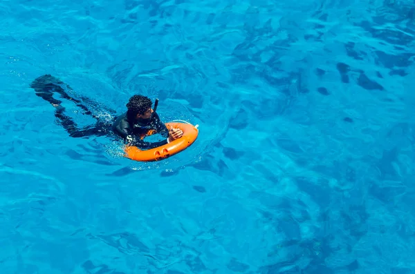 Sharm el Sheikh, Ägypten, 8. Mai 2019: Junger Mann mit Rettungsring schwimmt im meerblauen Wasser — Stockfoto