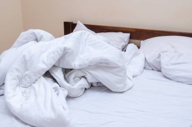 Yatak odasındaki yatağa buruşmuş beyaz yatak.