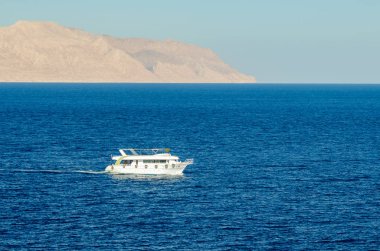 Kızıl Deniz 'in berrak mavi sularında seyahat eden yolcularla turistik bir tekne..