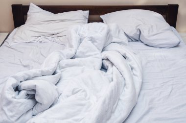 Yatak odasındaki yatağa buruşmuş beyaz yatak.